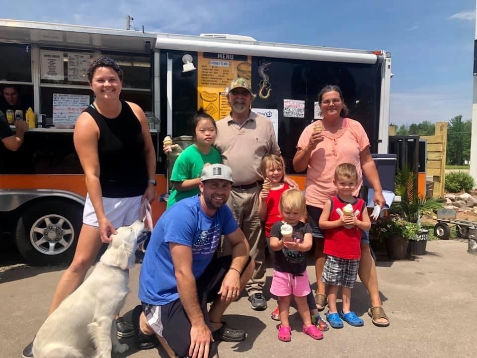 a family and their dog in front of the food truck